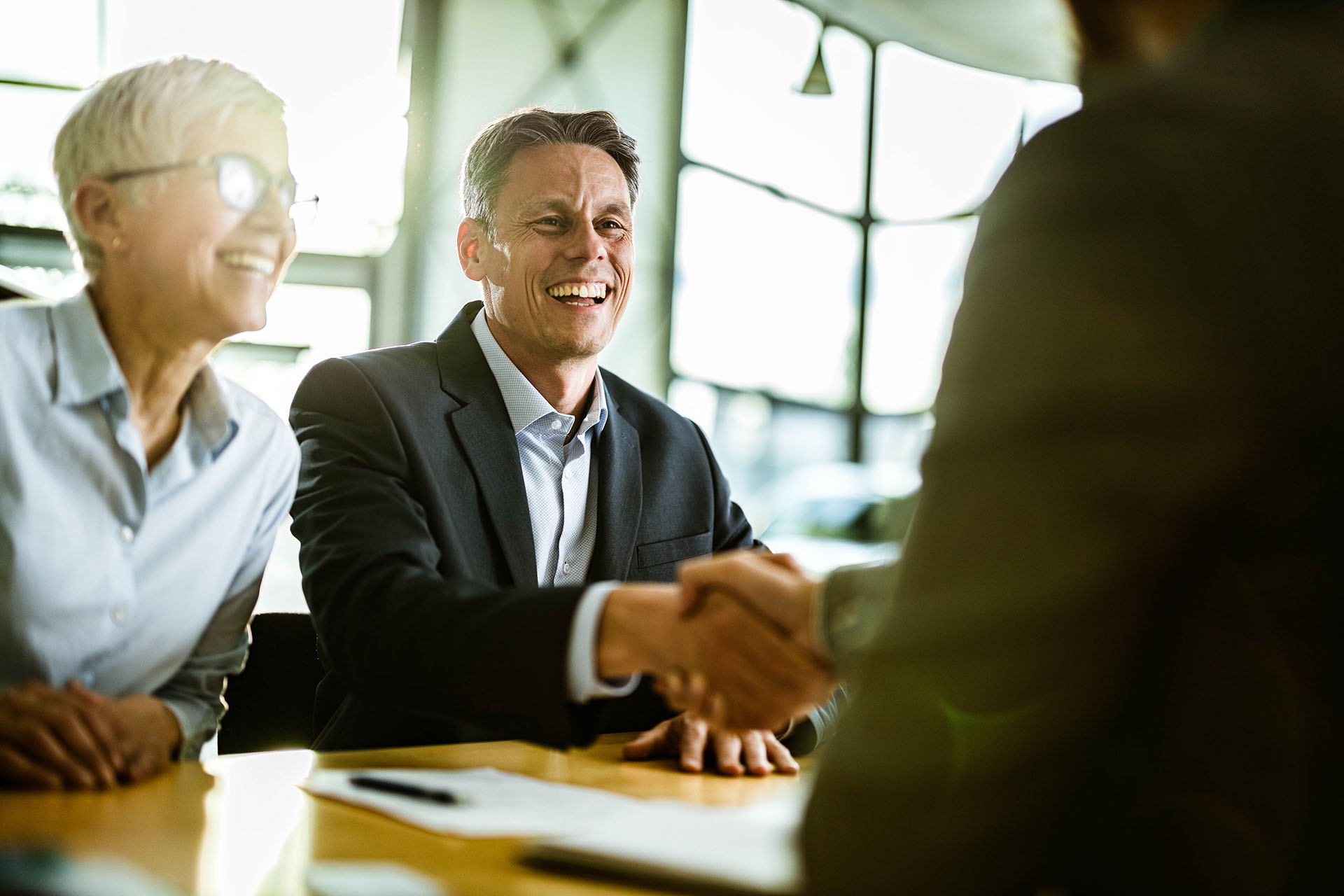 Happy business couple came to an agreement with their agent in the office.